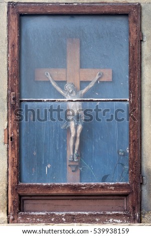 Jesus on the cross behind a window at an old house in Florence, Italy