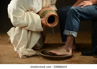 Jesus pouring water to wash feet of modern man over dark background