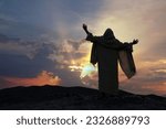 Jesus praying alone with raised hands on a hill at sunset. Biblical concept.