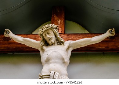 a Jesus statue on a cross carved from wood and painted