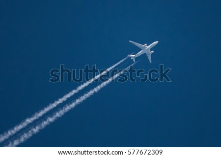 Jet airliner flying high in the sky leaves contrails in the clear blue sky