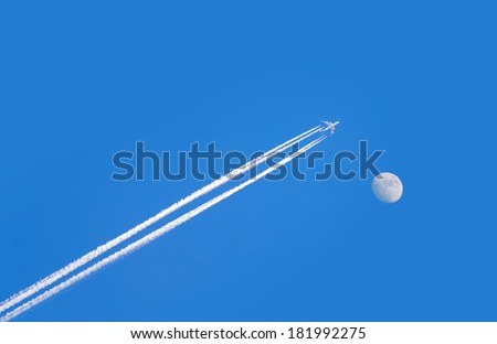 jet airplane with trail of fuel on blue sky and big moon