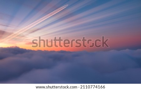 Jet airplane with trail of fuel on blue sky at sunset