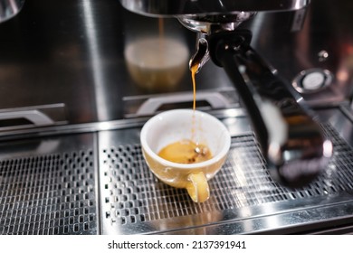 A jet of coffee pouring into a cup. Close-up coffee drops. Coffee making process.