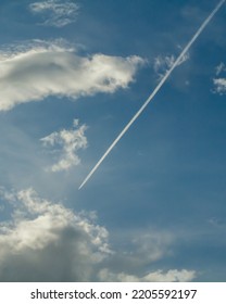 Jet Contrail In Blue Sky With Clouds