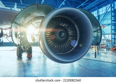 Jet engine with open hood covers on maintenance, illuminated by bright light from behind the hangar gate - Powered by Shutterstock