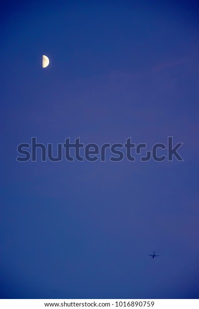 Jet and misty moon. Crescent moon. early moon\
and aircraft. Trip to the moon. lunar phase. Silhouette of landing\
airplane at rising of super-moon. aerspace airplane flying below.\
planetar satellite