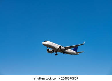 Jet Plane Before Landing Isolated On Blue Sky On A Summer Day In Frankfurt Germany. Aircraft Silhouette With Two Engines And Unfolded Landing Gear Seen From Ground At International Airport.