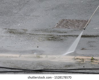 Jet Power Washer Hose Being Used To Clean Paint Off Road Surface. Road Cleaning With High Power Pressure Water Jet Hose