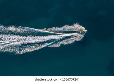 Jet Ski Rides A Wakeboarding In The Blue Sea. Aerial View