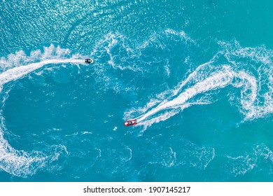 Jet Skiing In Open Waters. Aerial View, Summer Water Sport Recreational Background. Amazing Sea Ocean Lagoon. Aerial Drone Ultra Wide Photo Of Jet Ski Watercraft Couple Cruising In High Speed