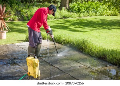 Jet Washing A Patio. Woman High Pressure Washing, Power Washing Or Cleaning A Garden Terrace, UK