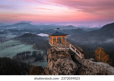 Jetrichovice, Czech Republic - Aerial view of Mariina Vyhlidka (Mary's view) lookout with foggy Czech autumn landscape and colorful pink sunrise sky in Bohemian Switzerland National Park