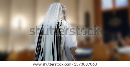 A Jew standing and praying in the synagogue with a prayer shawl (tallit) on his head