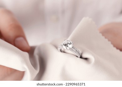 Jeweler cleaning diamond ring with microfiber cloth, closeup - Shutterstock ID 2290965371