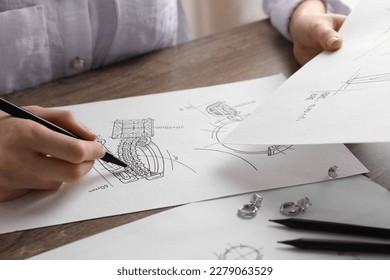 Jeweler drawing sketch of elegant earrings at wooden table, closeup - Powered by Shutterstock