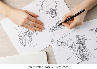 Jeweler drawing sketch of elegant ring on paper at wooden table, top view - Shutterstock ID 2277253979