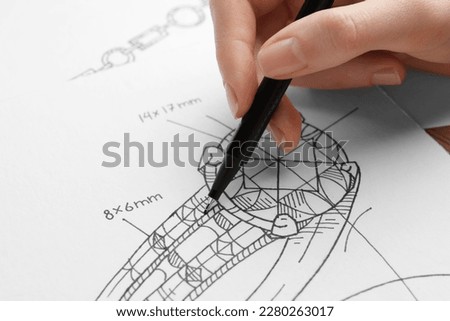 Jeweler drawing sketch of elegant ring on paper, closeup