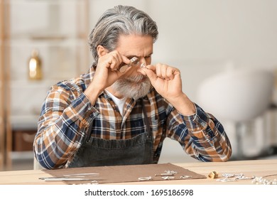 Jeweler Examining Adornment In Workshop