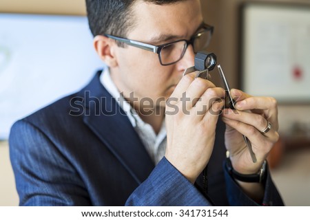 Jeweler examining diamond thoroughly through loupe