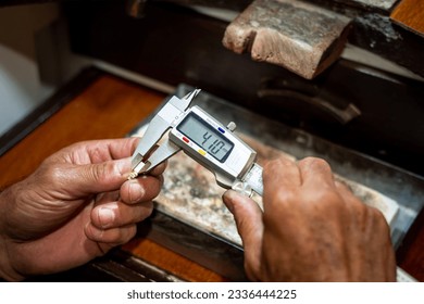 Jeweler hands measuring and checking gold jewel size with vernier caliper tool. Goldsmith working creating in his jewelry workshop. - Powered by Shutterstock