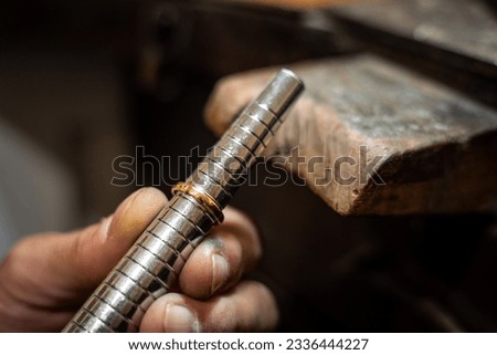 Jeweler hands measuring and checking ring size gauge mandrel. Goldsmith working repairing a gold jewel in his jewelry workshop.