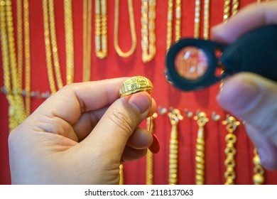 Jeweler Holding A Loupe For Check And Focus On A Gold Ring To Spot Fake Gold. Scams, Robberies, And Crimes In Gold Jewelry Shops. Valuable Assets For Investment. Store Of Wealth. Selective Focus.