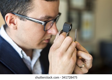 Jeweler Looking At Diamond Through Loupe To Inspect It