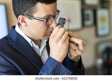 Jeweler Looking At Diamond Through Loupe To Inspect It