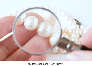 jeweler looking at pearl necklace through magnifying glass, jewerly inspect and verify