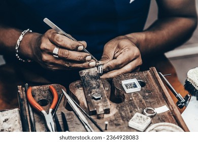 Jeweler making handmade jewelry on vintage workbench. Craft of jewelery making. Repairing ring by inlaid tight gem. - Powered by Shutterstock