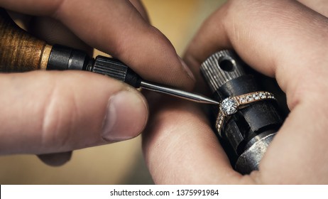 Jeweler repairing a gold ring, adjusting the gems on the product, close-up