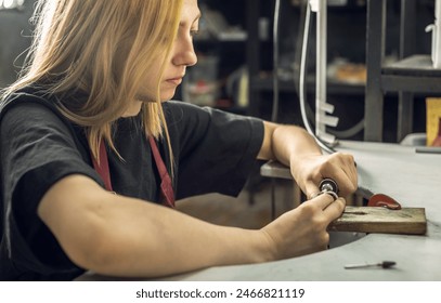 A jeweler uses a file to align a piece of jewelry in the form of a silver ring. Craft in a jewelry workshop. - Powered by Shutterstock