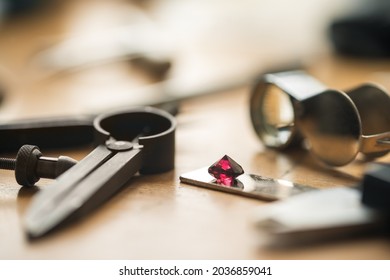 Jeweler's workplace. Side view of jeweler's workbenche with different tools and ruby on a wooden table. Goldsmith concept background