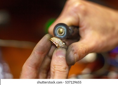 Jewelery polishing golden ring in workshop with adequate tools