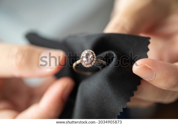 Jeweller\
cleaning jewelry diamond ring with fabric\
cloth