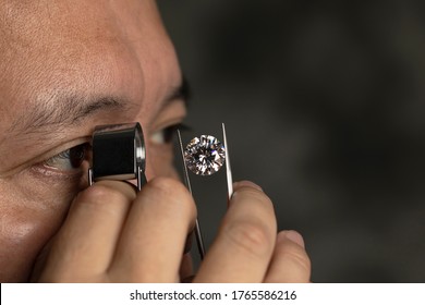 Jeweller examines polish round-cut diamond of large size. Close up photo of jeweller evaluating diamond through a magnifier. - Powered by Shutterstock