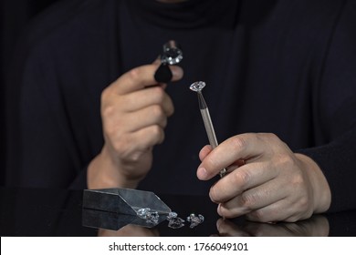 Jeweller examines polish round-cut diamond of large size. Close up of jeweller evaluating diamond through magnifier. Grading loose brilliant for certification. diamond trading business.