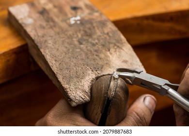 Jeweller using tongs to place a precious stone on top of a silver ring in a craftsman's workshop - Powered by Shutterstock