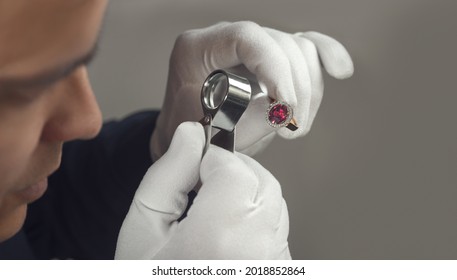 Jeweller at work. Male jeweler examining gold ruby and diamond ring. Jewelry master goldsmith examines the gold ring for defects, close-up - Powered by Shutterstock