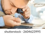 Jewellery inspector doing visual examination of jewelry ring, experienced male jeweler detects damages, quality, price for jewelry trader and gem expert with magnifying glass or jeweler