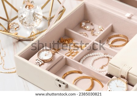 Jewelry box with many different accessories and perfume on white marble table, closeup