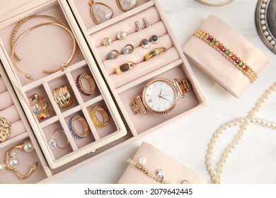 Jewelry box with stylish golden bijouterie on white table, flat lay