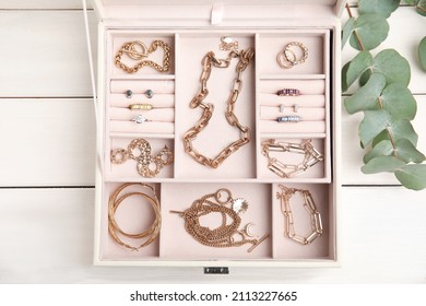 Jewelry box with stylish golden bijouterie on white wooden table, flat lay