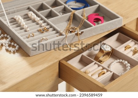 Jewelry boxes with many different accessories on wooden table, closeup