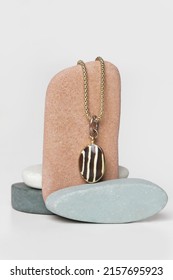 Jewelry Fashion Photography. Gold Necklace With Pendant Displayed On Decorative Stones, Studio Product Shot.
