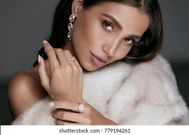 Jewelry Fashion. Woman In Luxury Jewels. Glamour Female Model With Beauty Face Makeup Wearing Expensive Gold Jewelry And Stylish Beige Mink Fur Coat. High Quality Image.