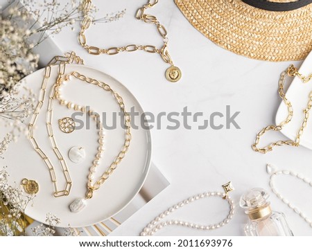 Jewelry lifestyle flat layout with place for text. Jewellery background. Top view marble table with beautiful and stylish golden and pearl necklaces, chains and elegant pendants. Fashion accessories.