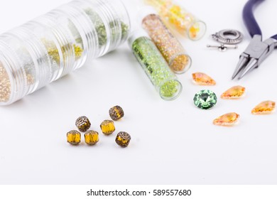 Jewelry Making And Beading Process. Glass Seed Beads, Turquoise Stones, Silver Toggle, Earrings And Pliers On White Background. Selective Focus.