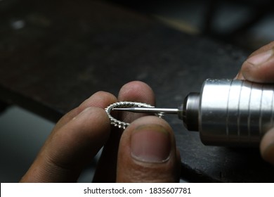 Jewelry making: Jeweler using engraving drill mounted on flexible shaft machine to enlarge holes inside ring, preparing for stone setting process.